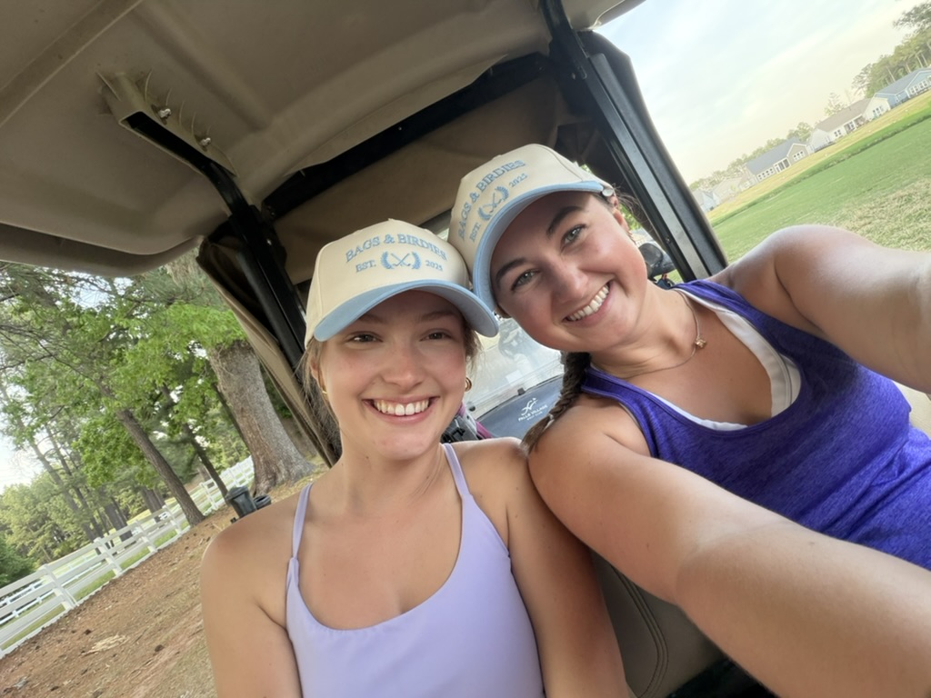 The two founders of Bags & Birdies in their branded hats, in a golf cart
